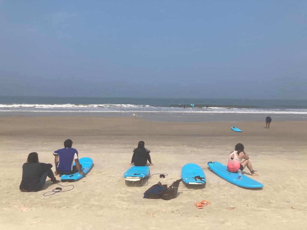 People sitting on surfboards watching others coming out of the water